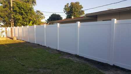 this picture is of a new white fence surrounding a property and completed by Fort Lauderdale Pavers